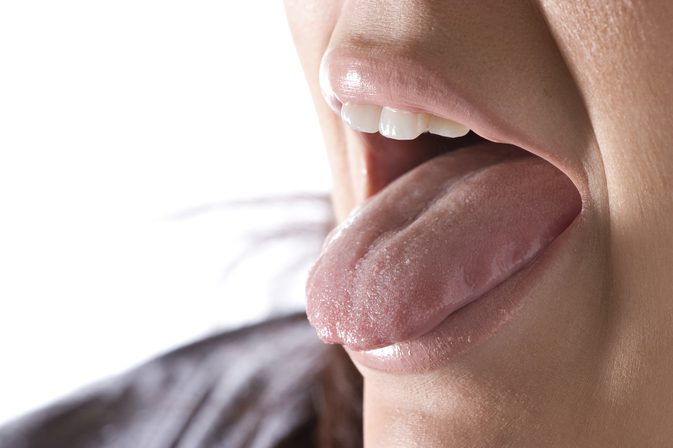 Hva forårsaker en hvit belegg på tungen?