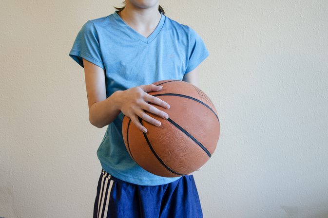 Een basketbal pakken met kleine handen